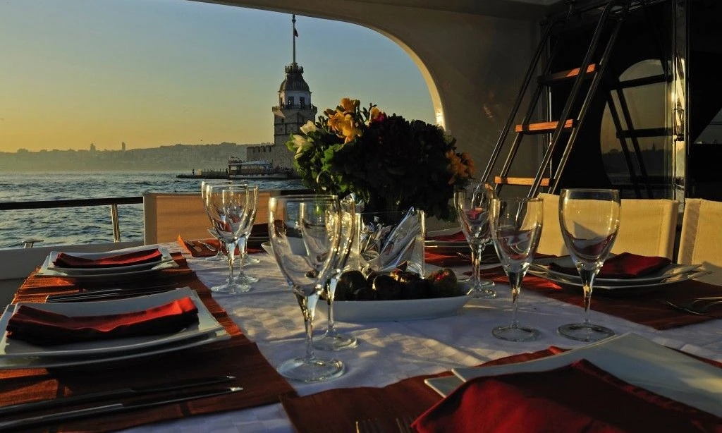  dining table on a boat with a sunset view over the Bosphorus, with the Maiden's Tower in the background.